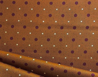 May include: Brown fabric with a repeating pattern of small white and dark purple polka dots.