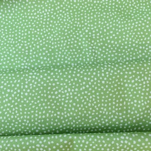 May include: Green fabric with a white polka dot pattern. The fabric has a subtle sheen and a soft texture.