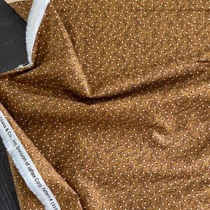 May include: Brown fabric with a white and brown repeating pattern of small circles connected by thin lines. The fabric has a white selvage with the text "Glass & Co... Inc Division of Jaftex Corp. Pattern # 1519 www.henryglass.com".