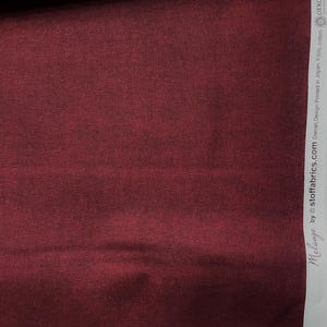 May include: A close-up of a deep burgundy fabric with a subtle texture. The fabric is 100% cotton and is printed in Japan. The fabric is certified by OEKO-TEX Standard 100, which means it is free of harmful chemicals.