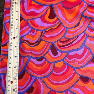 May include: A fabric with a repeating pattern of overlapping, concentric circles in shades of orange, red, and purple. The circles are outlined in blue.