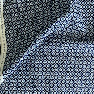 May include: A navy blue fabric with a repeating pattern of white and light blue stylized flowers in a diamond shape. The fabric has the text "Part No. 3544 - 77 © A.J.'s Watercolor Studio for The Blank Quilting Corp. - Enjoli Plus 8"