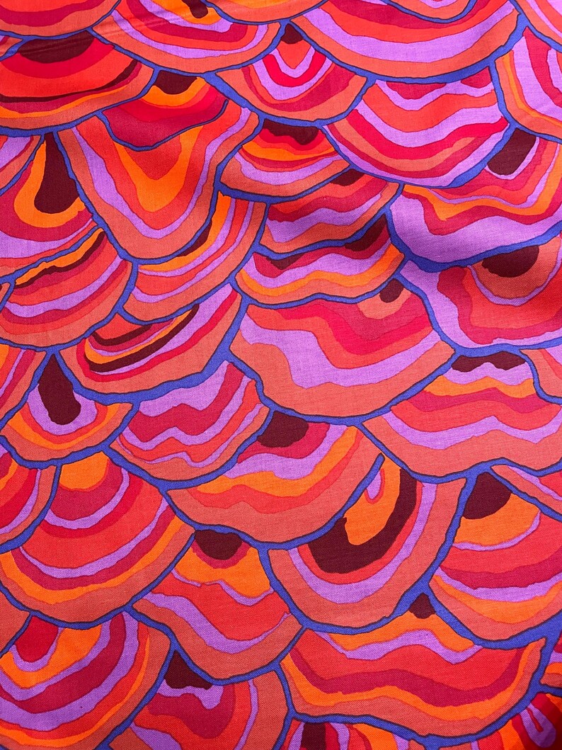 May include: Abstract fabric with a repeating pattern of overlapping, concentric circles in shades of red, orange, purple, and blue.
