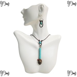 May include: A turquoise and brown leather necklace with a pendant featuring a turquoise stone and a metal charm. Matching turquoise and brown leather earrings with a turquoise stone dangle.