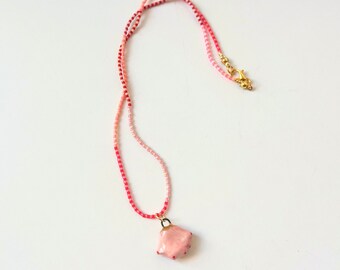 Miyuki Delica bead necklace with striped bands of reds and pinks ,and a tiny pink hand porcelain pendant with gold detail and tiny red nails