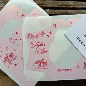 Puede incluir: Adhesivos de color rosa claro para c&aacute;maras con ilustraciones de l&iacute;nea roja de una bola de discoteca, copas de champ&aacute;n, corazones y estrellas. El texto dice "BRIDE", "Taylor's Hens" y "26.10.2029". Se ve una tarjeta de instrucciones.