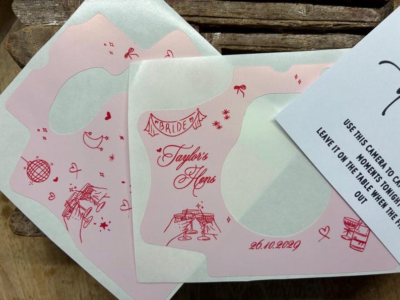 Puede incluir: Adhesivos de color rosa claro para c&aacute;maras con ilustraciones de l&iacute;nea roja de una bola de discoteca, copas de champ&aacute;n, corazones y estrellas. El texto dice "BRIDE", "Taylor's Hens" y "26.10.2029". Se ve una tarjeta de instrucciones.