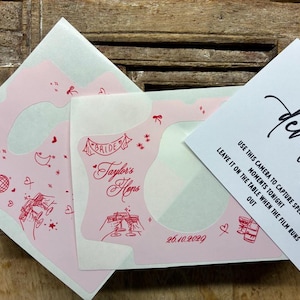 Puede incluir: Una funda de c&aacute;mara rosa claro con dibujos lineales rojos de una bola de discoteca, copas de champ&aacute;n, corazones y estrellas. El texto dice Taylor's Hens, Bride y 26.10.2029. Una tarjeta blanca adjunta dice Can't wait to see how it develops.