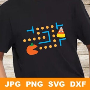 Puede incluir: Una camiseta negra con un diseño de Pac-Man con una calabaza y un caramelo de maíz. El diseño incluye un laberinto azul con puntos naranjas.