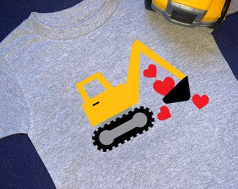 May include: A gray t-shirt with a yellow construction vehicle design. The vehicle is digging up red hearts.