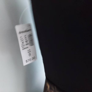 May include: A black garment with a white tag attached. The tag displays the size as 8.