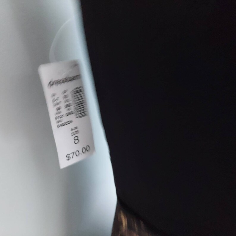 May include: A black garment with a white tag attached. The tag displays the size as 8.