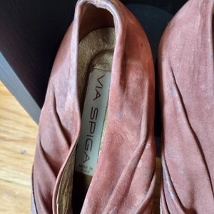 A pair of brown leather shoes with the brand name "VIA SPIGA" and the text "MADE IN ITALY" on the inside of one shoe. These mules are slip-on style, Vintage Italian leather, embossed as crocodile pattern. This photo depicts the ruched cuff of suede.
