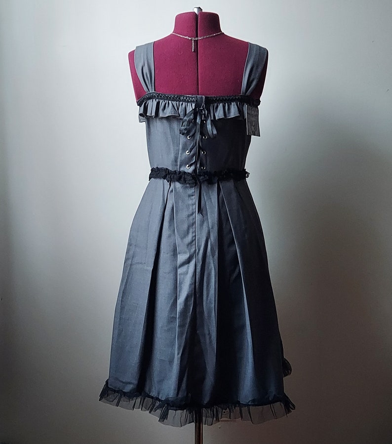 Op de afbeelding: Een grijze en zwarte jurk met een kantversiering en een corset-stijl lijfje. De jurk heeft een getailleerd lijfje en een volle rok.