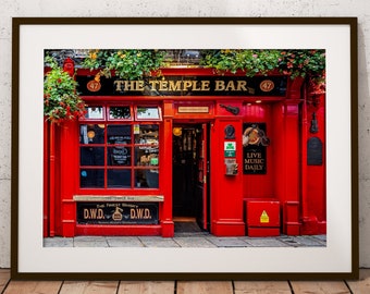 May include: A framed print of The Temple Bar in Dublin, Ireland. The pub's red facade is adorned with the name in white lettering and green foliage. The entrance is open, inviting viewers to step inside.