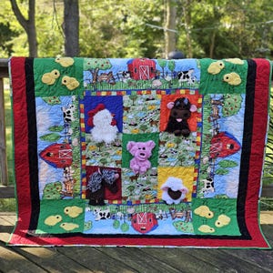 May include: A colorful farm-themed quilt with appliqued farm animals and barnyard scenes. The quilt features a red border, green and blue squares, and various farm animals like a cow, pig, and sheep. The quilt is approximately 60 inches by 70 inches.