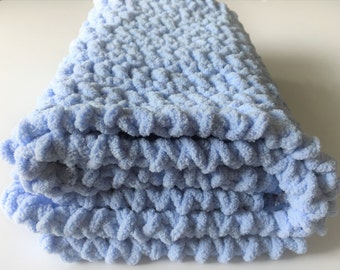 May include: A soft, light blue knitted baby blanket with a textured, fluffy surface.