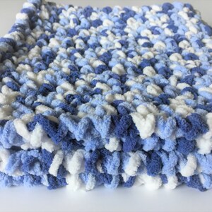 May include: A soft, blue and white knitted baby blanket with a fluffy texture.
