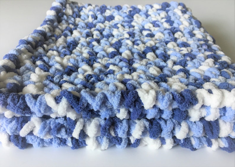 May include: A soft, blue and white knitted baby blanket with a fluffy texture.