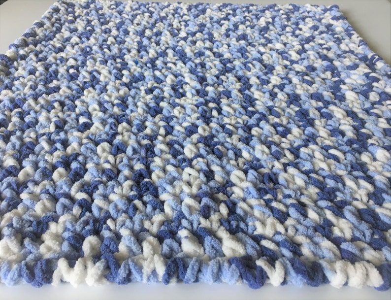 May include: A soft, blue and white knitted baby blanket with a fluffy texture.