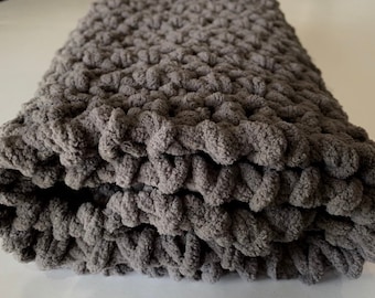 May include: A gray chunky knit throw blanket with a soft, fuzzy texture.