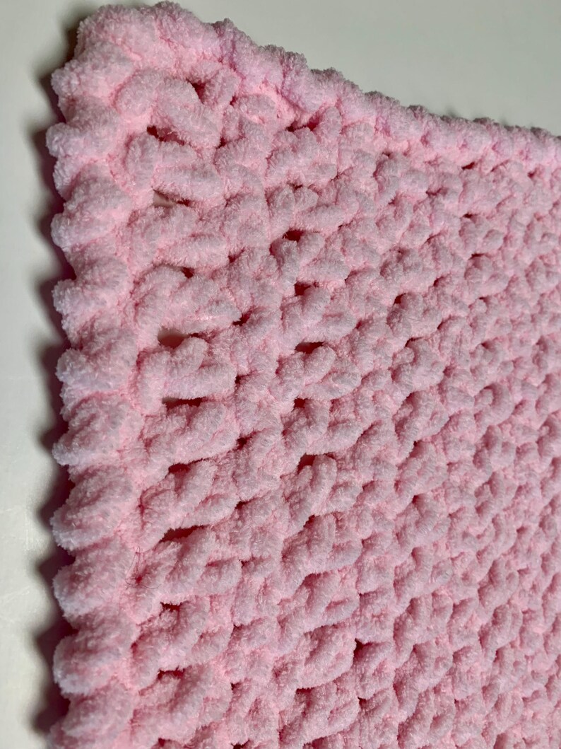 May include: A soft, pink crocheted baby blanket with a textured stitch pattern.