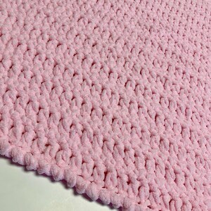 May include: A soft, pink crocheted blanket with a textured, fluffy surface.
