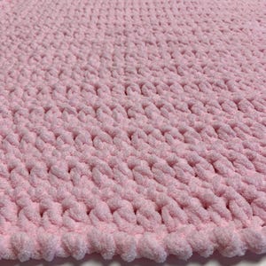 May include: A soft, pink knitted baby blanket with a textured, chunky knit pattern.