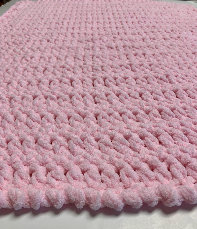 May include: A soft, pink knitted baby blanket with a textured, chunky knit pattern.