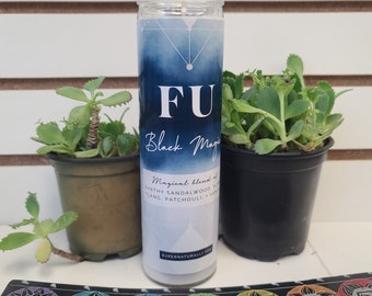 May include: A white candle with a blue and white label that says "FU Black Magic" and "Magical blend of Earthy Sandalwood, Ylang, Patchouli, Vanilla". The candle is sitting on a table with a rainbow-colored background.