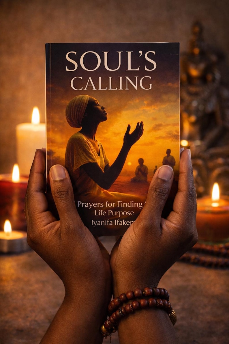 May include: A book titled "SOUL'S CALLING" is held in dark hands, with the cover showing a person looking up at a sunset. The book's subtitle reads "Prayers for Finding Life Purpose" by Iyanifa Ifakemi. Lit candles and a beaded bracelet are in the background.