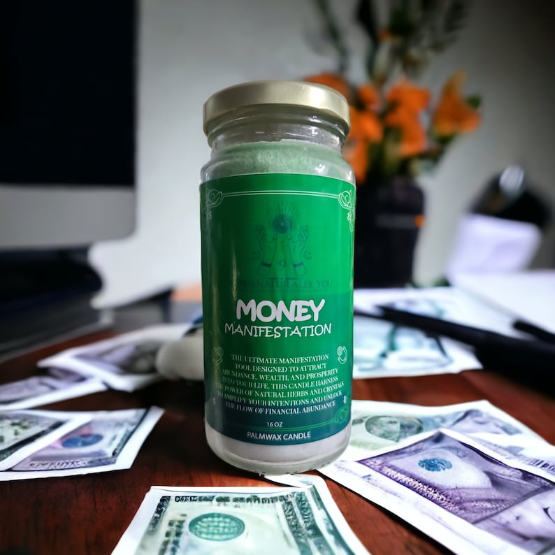 May include: A green glass jar candle with a gold lid. The label reads "Money Manifestation" and includes the text "The ultimate manifestation tool designed to attract abundance, wealth and prosperity in your life. This candle harnesses the power of natural herbs and crystals to amplify your intentions and unlock the flow of financial abundance. PalmWax Candle 16 oz."