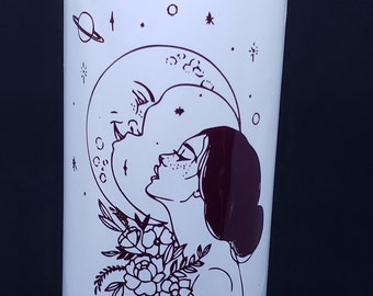 Puede incluir: Vela de cristal rosa con una etiqueta blanca que dice "THE LOVERS maqick" y presenta una ilustración en blanco y negro de dos personas abrazándose bajo una luna creciente. La etiqueta también dice "Rose Quartz + Verbena Infused Spell Candle" y "SUPERNATURALLY YOU".