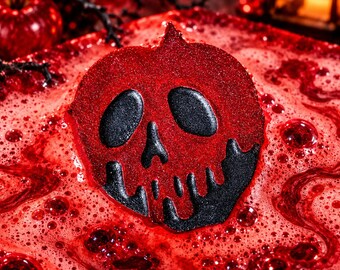 May include: A round, glittery red bath bomb shaped like a poisoned apple with a black skull design in the center. The bath bomb is partially submerged in vibrant red bath water, creating a swirling effect with numerous bubbles on the surface.