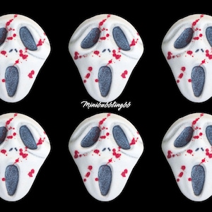 May include: Six white, Scream mask-shaped bath bombs with gray eye and mouth details and red splatter accents. The bath bombs are arranged on a black background. The text "minibubblingbb" is in the center.