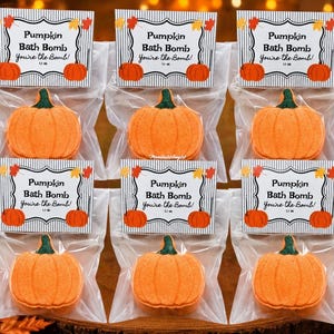 May include: Six individual pumpkin-shaped bath bombs packaged in clear plastic bags. Each bag features a white header card with black vertical stripes, orange pumpkin illustrations, and the text Pumpkin Bath Bomb You're the Bomb 1.1 oz.