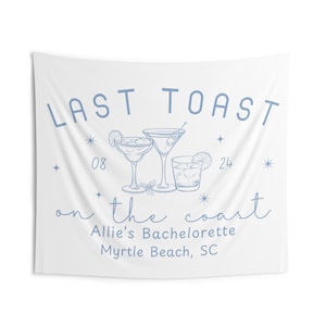 May include: White tapestry with blue text and illustrations. The words "LAST TOAST" are at the top, with "08 24" below. Illustrations of cocktails are in the centre, with "on the coast" and "Allie's Bachelorette Myrtle Beach, SC" below.