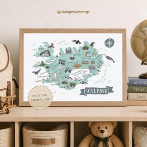Op de afbeelding: Een ingelijste print van IJsland, met een gedetailleerde kaart met illustraties van bezienswaardigheden en dieren. De kaart is in tinten blauw en groen, met de tekst "ICELAND" en "DIGITALE DOWNLOAD".