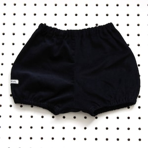May include: Black corduroy baby bloomers with a white tag that says "Kids".