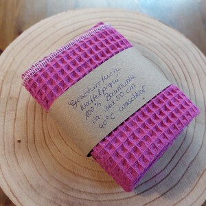 K&ouml;nnte beinhalten: Ein pinkfarbenes Waffeltuch aus 100% Baumwolle. Das Tuch ist mit "Geschirrtuch, Waffel Piqu&eacute;, 100% Baumwolle, ca. 36x 50 cm, 40&deg;C waschbar" beschriftet.