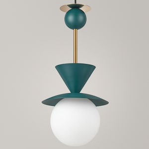 May include: A pendant light fixture featuring a matte teal finish with gold-toned accents. The design includes a spherical teal element, a conical shade, a flat circular disc, and a large white glass globe at the base, suspended by a rod.