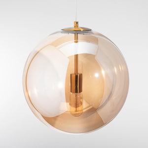Könnte beinhalten: Eine moderne Pendelleuchte mit einem kugelförmigen, bernsteinfarbenen Glasschirm. Die Leuchte hat einen goldfarbenen Metallstiel und eine kleine, freiliegende Glühbirne. Das Design ist minimalistisch und für verschiedene Einrichtungsstile geeignet.