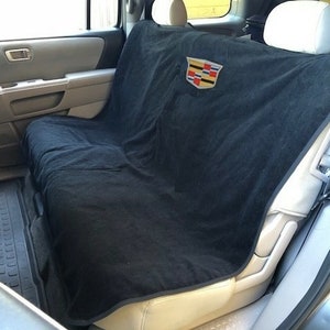 May include: Black car seat cover with a Cadillac logo embroidered in the center. The cover is made of a soft, plush material and is designed to protect your car seats from dirt, spills, and pet hair.
