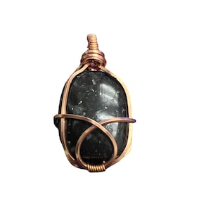 May include: A black stone pendant wrapped in copper wire. The stone has a speckled appearance.