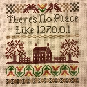 May include: Cross-stitch embroidery featuring a brown house, trees, and flowers. The text reads "There's No Place Like 127001."