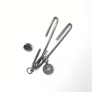 May include: A silver metal owl charm with a silver metal ring attached to a silver metal chain. The chain is connected to two silver metal hooks.