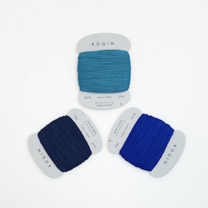 Puede incluir: Tres carretes de hilo de algodón 20/8 en azul, azul oscuro y turquesa. Cada carrete está etiquetado con "KOGIN" e incluye el texto "cotton 100%", "daruma-ite.co.jp" y "MADE IN JAPAN".