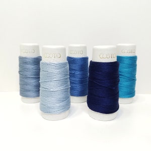 May include: Five spools of thread in shades of blue, from light to dark, with the word "cosmo" printed on each spool.