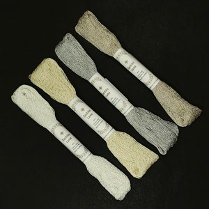 May include: Four spools of metallic embroidery thread in silver, gold, beige, and light gray. Each spool is labeled "Sashiko Lame" with the color name and "Cotton Silk, Embroidery Thread, Made in Japan."