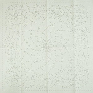 May include: A square, off-white fabric with a detailed, dotted-line design. The pattern features a large central circle with a starburst design, surrounded by smaller circles and floral elements. The design is likely for embroidery or quilting.